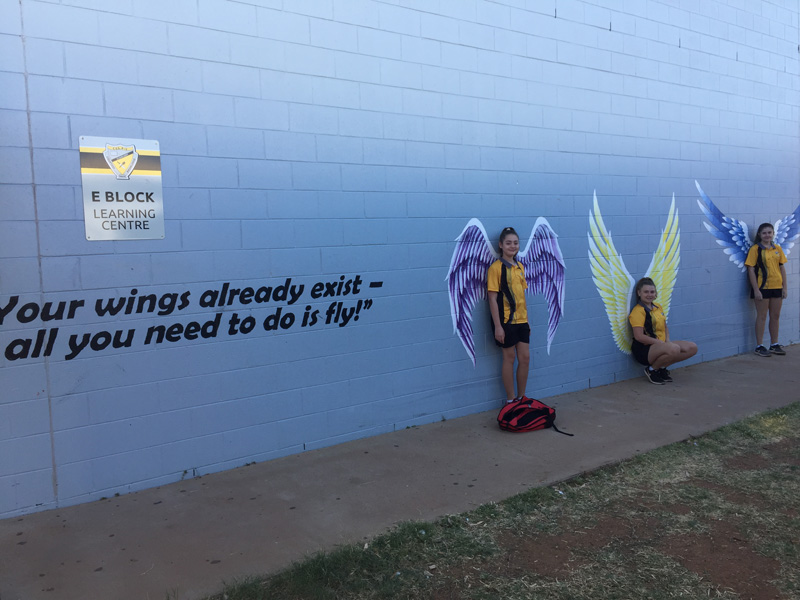 Students leaning against an artwork mural